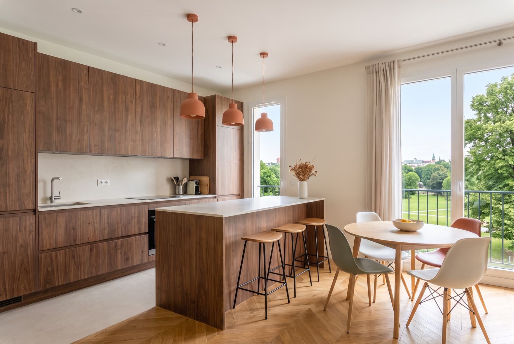 A23's walnut kitchen annex, stone-topped breakfast island, terracotta pendants and greenery outside the window