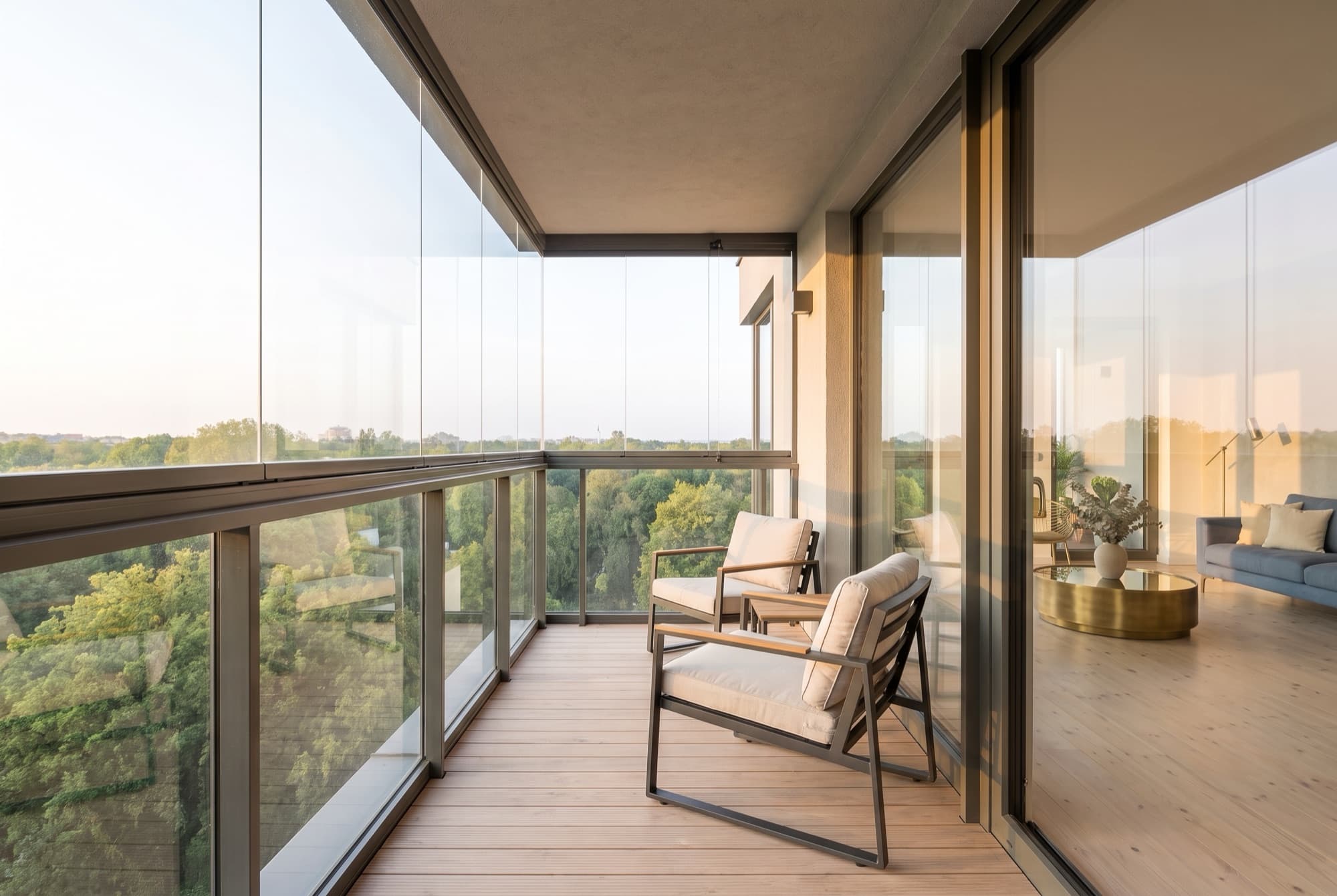 The recessed, glazed-in loggia of A40, wood decking and two armchairs sheltered above Park Lotników