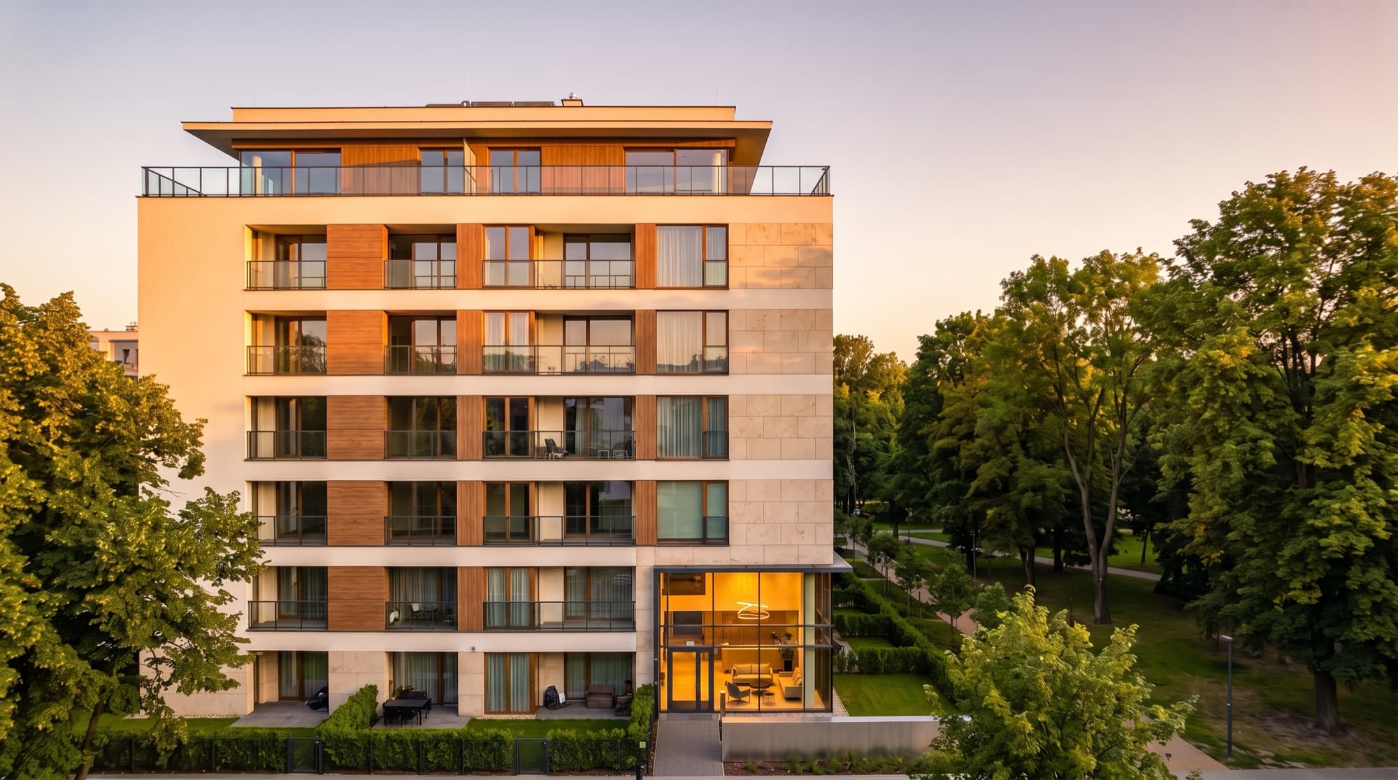 Building 1 in Kraków at golden hour: a calm eight-storey mid-rise beside the park, with ground-floor gardens
