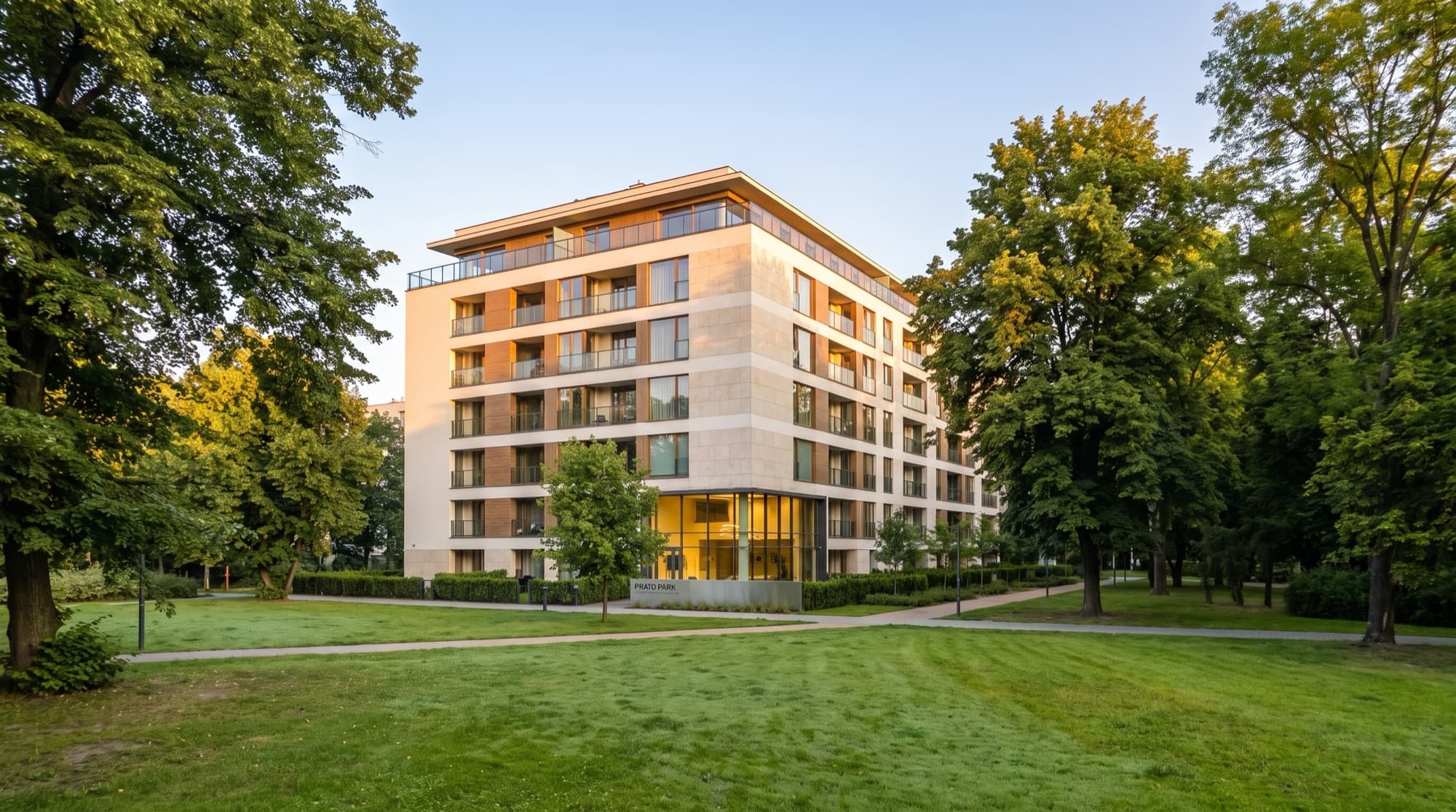 Building 1 seen across the lawns and mature trees of the neighbouring park in Czyżyny, Kraków
