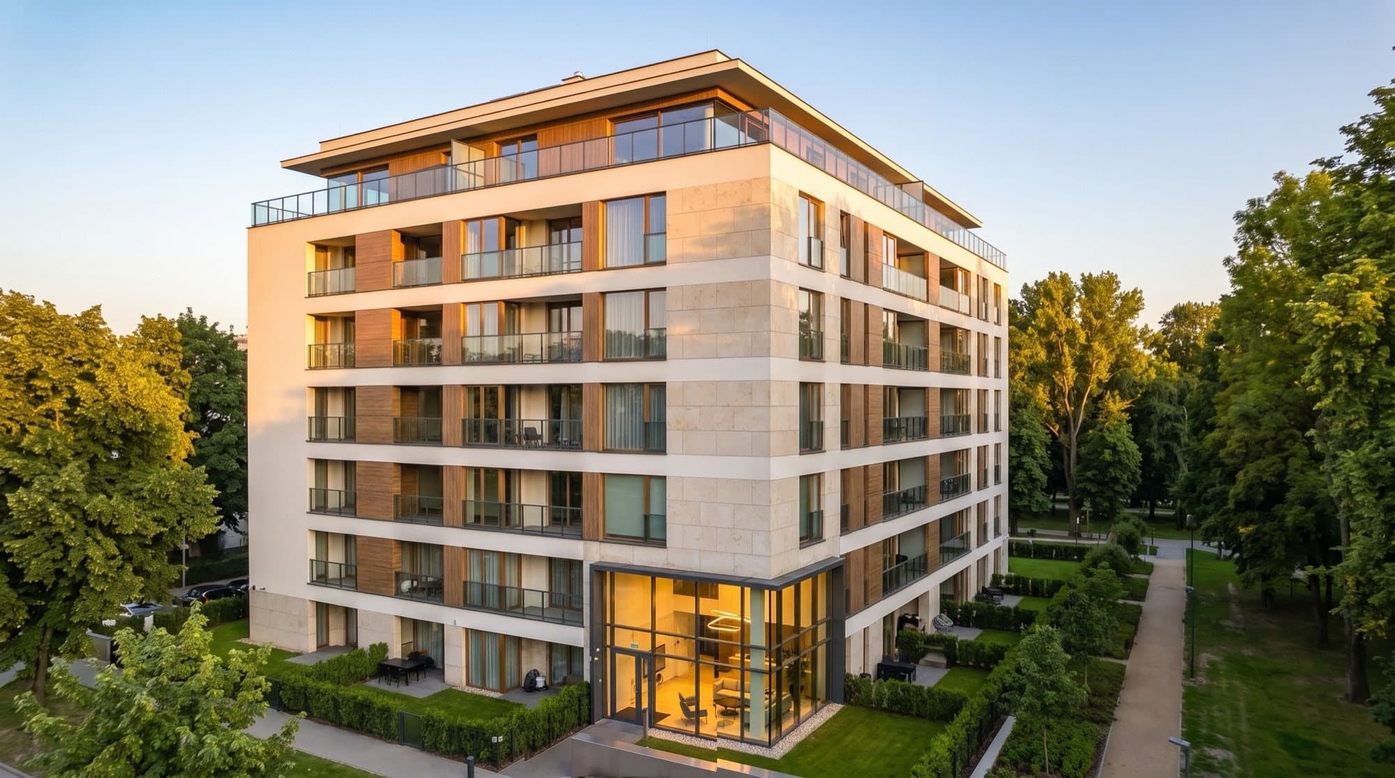 Building 1 from its corner at golden hour, balconies and timber panels above the landscaped gardens